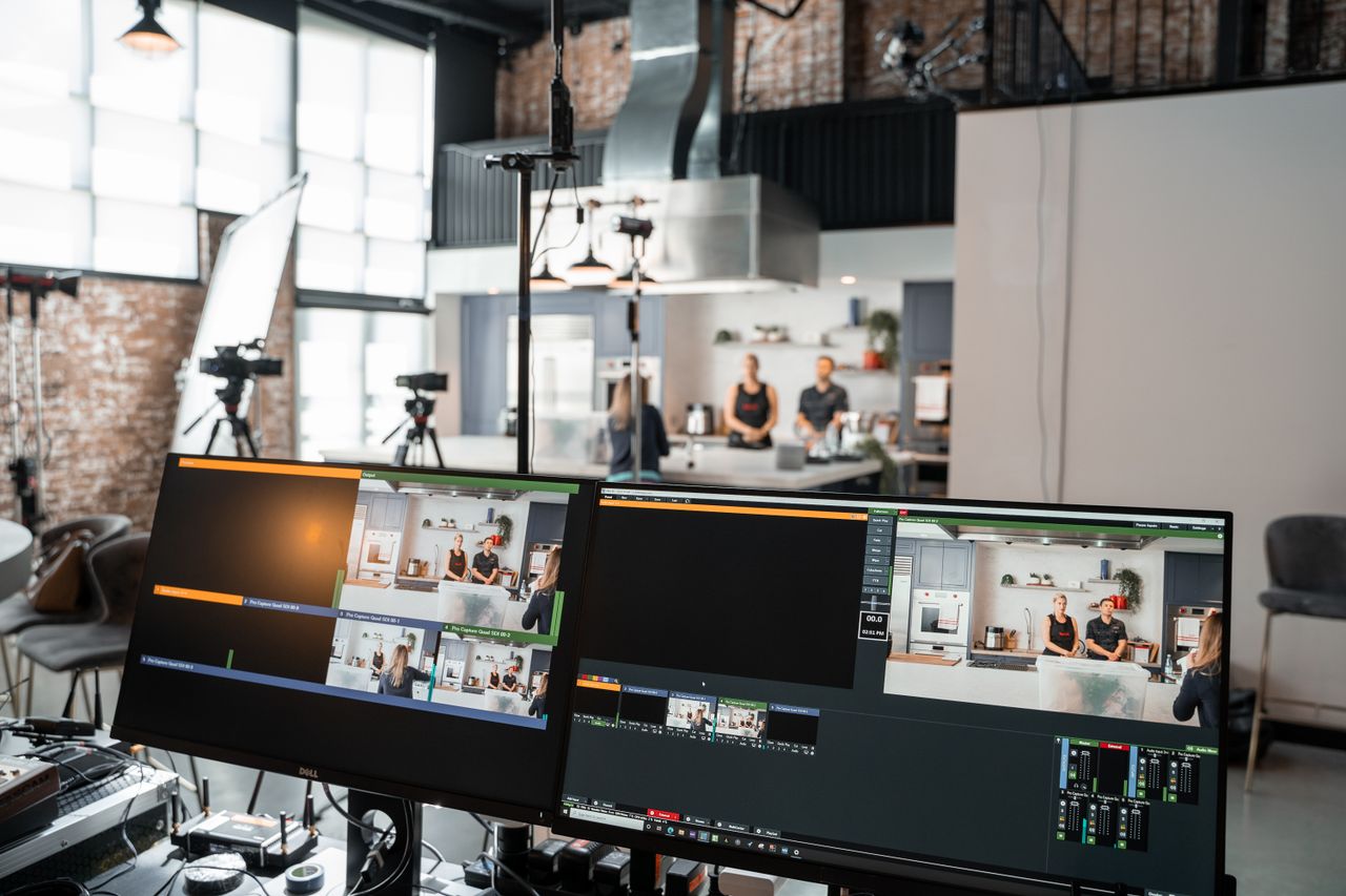 vision A dynamic setup in a video production studio with two monitors and a kitchen setting.