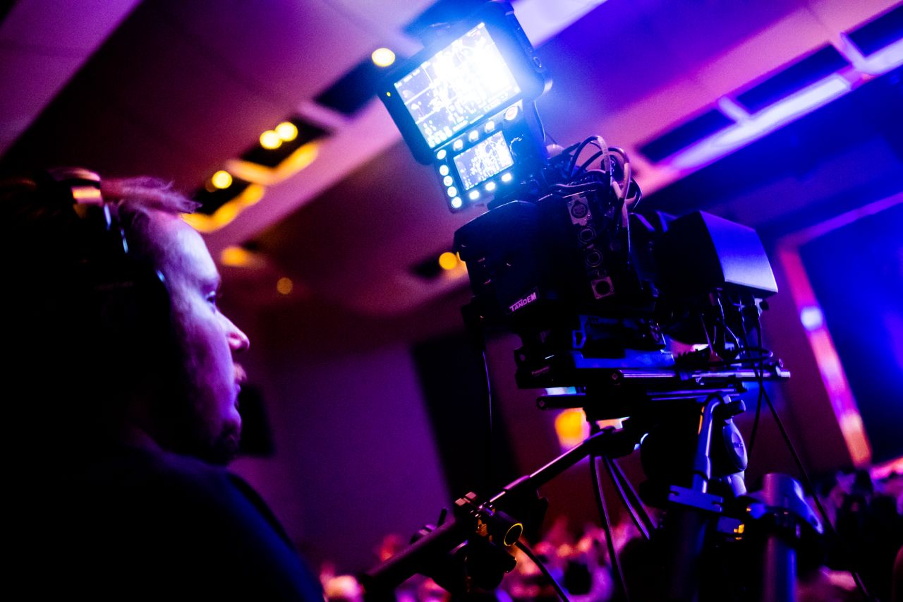 gallery-01 A professional cameraman operating a camera during a vibrant nightlife event indoors.