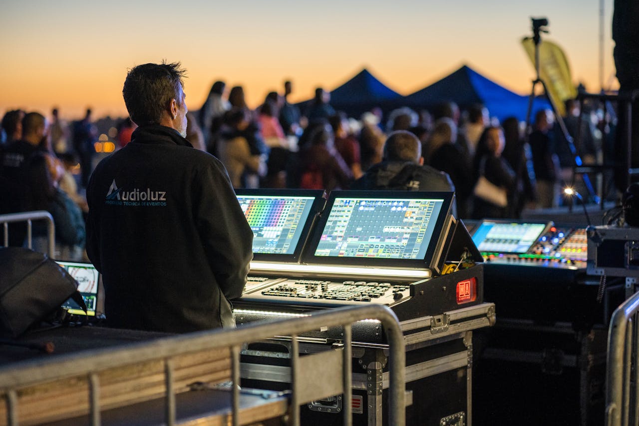 services-img Technician managing sound and lighting panels during an outdoor event at sunset.