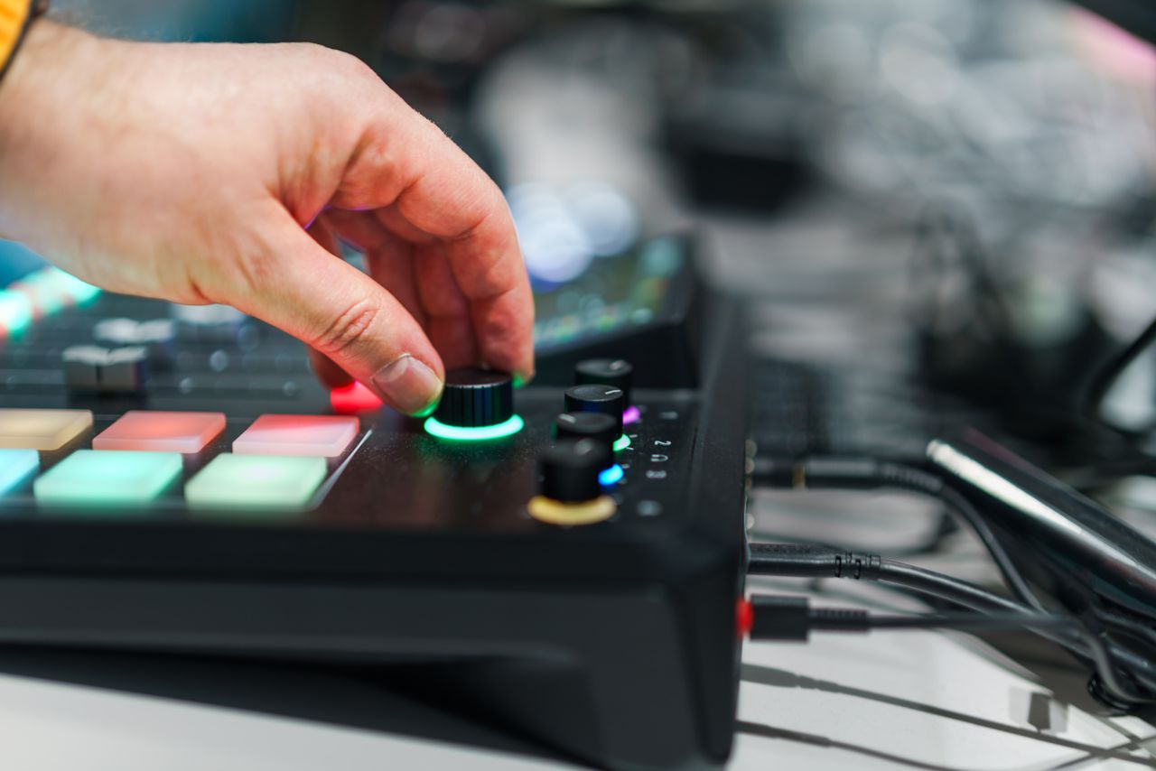 trusted-partner Close-up of a hand adjusting knobs on an audio mixer in a studio setting, highlighting modern sound equipment.