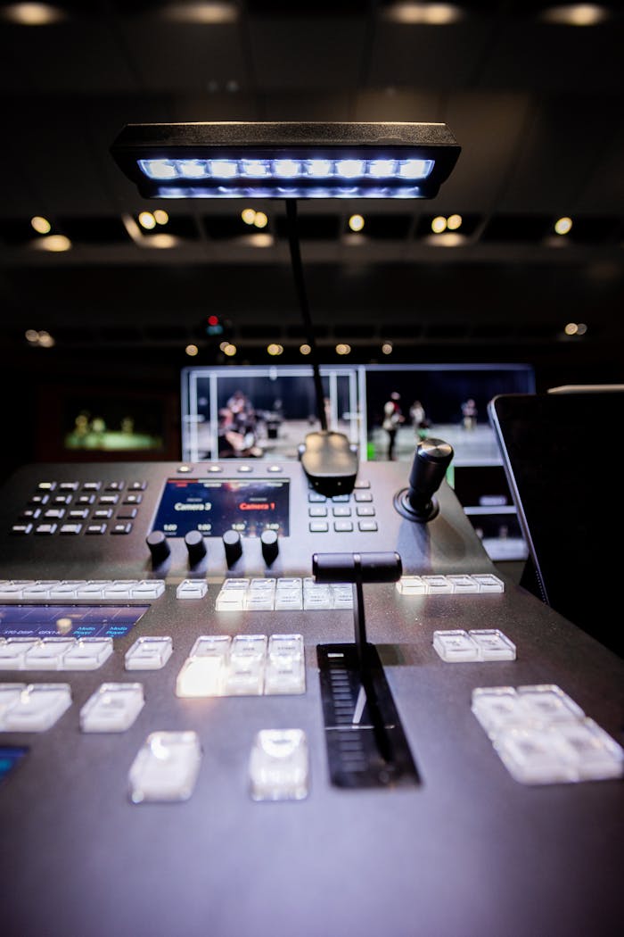 services-01 Contemporary shiny audio mixer controller with buttons and switches under illuminated lamp in modern studio