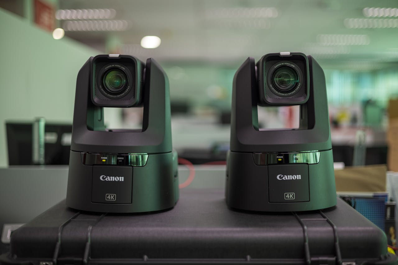 gallery-04 Two professional Canon 4K video cameras displayed on a protective case in an office setting.