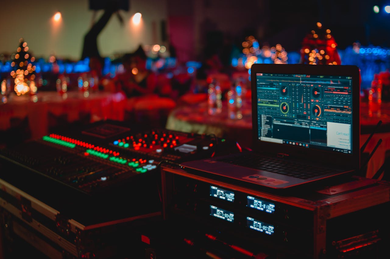 gallery-05 Vivid DJ setup with laptop and sound mixer at a lively indoor event.