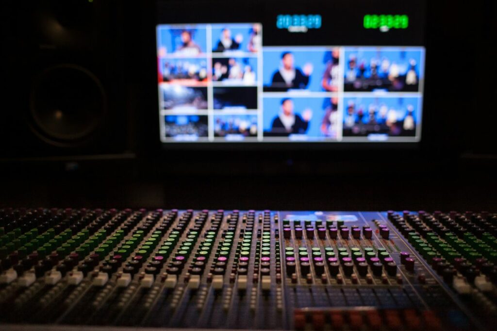 pexels photo 13627258 13627258 Close-up of a sound mixer with screens displaying video feeds in a professional studio setup.